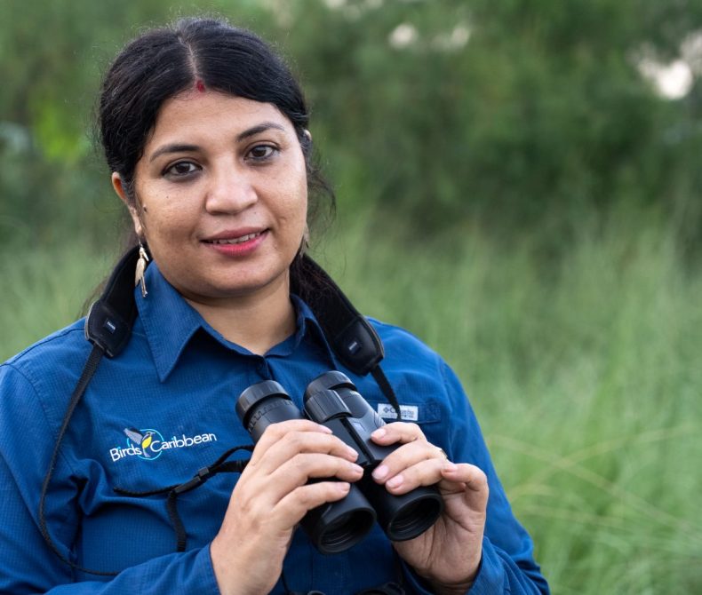 Dr Purnima Barman in a green field with binnoculars